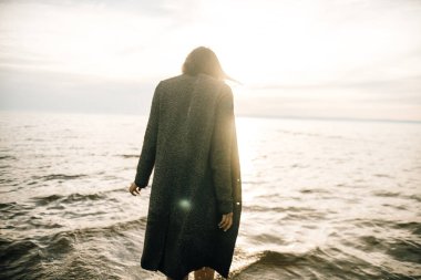 Plajda siyah elbiseli bir kadın kırık bir gemiyle