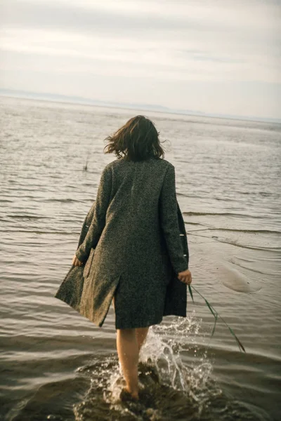 穿着黑色衣服的女人在海滩上与破碎的船 — 图库照片