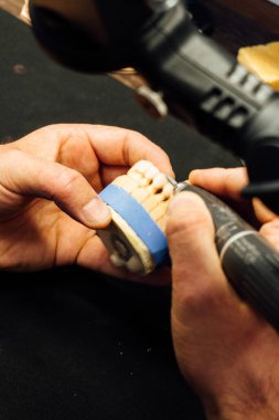 Diş teknisyeninin elleri bireysel alçı çene, yakın çekim, diş hekimliği ve süreç ayrıntıları kavramını oluşturan elleri  