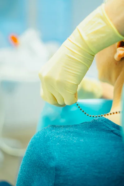 Dental doctor in medical glove putting dental bibs on patient, close view