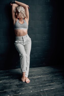 Sarışın, güzel, şık elbiseli, tavan arasında poz veren bir kadın.  