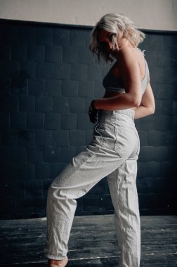 Sarışın, güzel, şık elbiseli, tavan arasında poz veren bir kadın.  