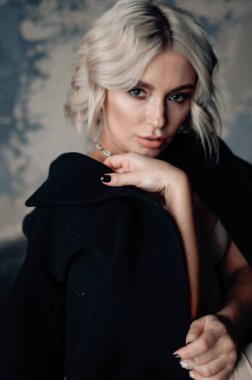 Sarışın, güzel, şık elbiseli, tavan arasında poz veren bir kadın.  