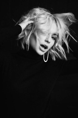 Sarışın, güzel, şık elbiseli, tavan arasında poz veren bir kadın.  