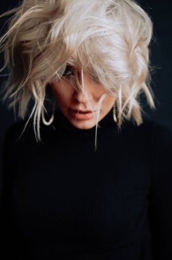 Sarışın, güzel, şık elbiseli, tavan arasında poz veren bir kadın.  