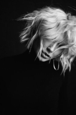 Sarışın, güzel, şık elbiseli, tavan arasında poz veren bir kadın.  