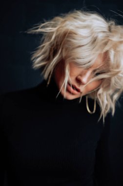 Sarışın, güzel, şık elbiseli, tavan arasında poz veren bir kadın.  