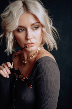 Sarışın, güzel, şık elbiseli, tavan arasında poz veren bir kadın.  