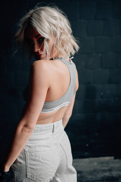 блондинка красивая молодая женщина в стильной одежде позирует в интерьере лофта
  