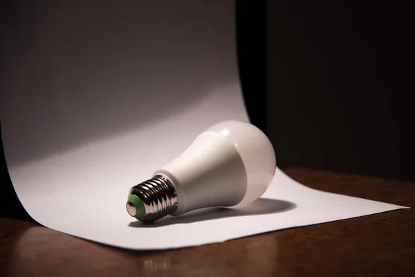 white light bulb lying on a white piece of paper