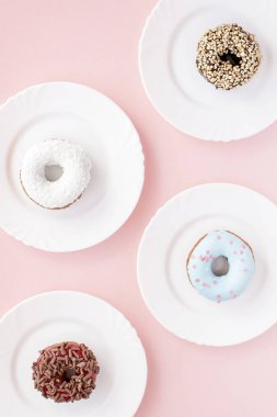 Sır pembe bir arka plan üzerinde dört beyaz tabaklar farklı çörek ile kaplı