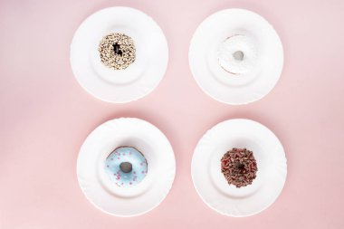 Dört çeşit: pembe bir arka plan üzerinde beyaz bir tabakta donut