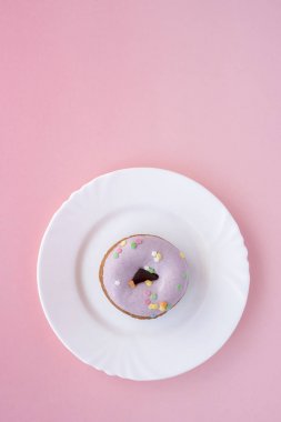 Mor pembe bir arka plan üzerinde beyaz bir plaka üzerinde buzlanma çörek kaplı