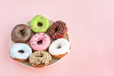 Çörek sır çeşitli ile kaplı ve tatlılar bir plaka üzerinde pembe bir arka plan üzerinde serpilir