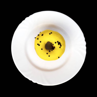 Çörek sarı sır ile kaplı ve siyah arka plan üzerine beyaz plaka üzerinde siyah madalyonun serpilir