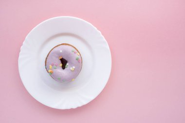 Mor pembe bir arka plan üzerinde beyaz bir plaka üzerinde buzlanma çörek kaplı