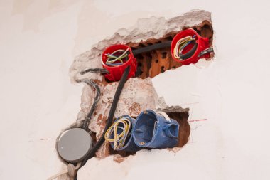 Duvardaki soket kutularından kablolar çıkıyor.