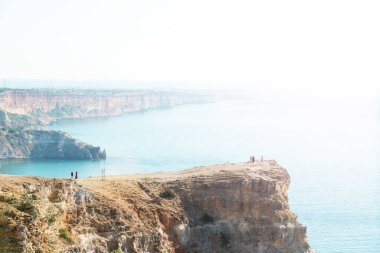 Deniz kıyısındaki yüksek kıyılar ve kıyıdaki insanlar. Güneşli bir yaz günü. Cape Fiolent, Kırım Temmuz 'da