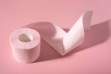 Pembe arka planda pembe bir tuvalet kağıdı rulosu. Hijyen ürünleri.