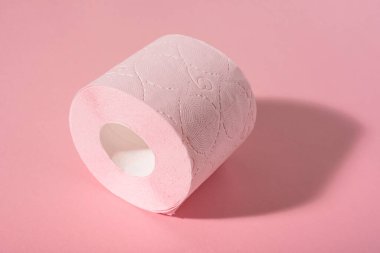 Pembe arka planda pembe bir tuvalet kağıdı rulosu. Hijyen ürünleri.