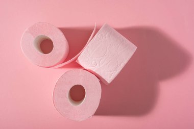 Pembe arka planda üç rulo pembe tuvalet kağıdı. Hijyen ürünleri. Üst Manzara. Boşluğu kopyala.