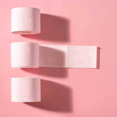Pembe arka planda üç rulo pembe tuvalet kağıdı. Hijyen ürünleri. Üst Manzara. Boşluğu kopyala.