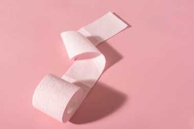 Pembe arka planda pembe bir tuvalet kağıdı rulosu. Hijyen ürünleri.
