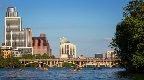 在德克萨斯州的奥斯汀天际线在白天与皮划艇享受科罗拉多河 图库图片