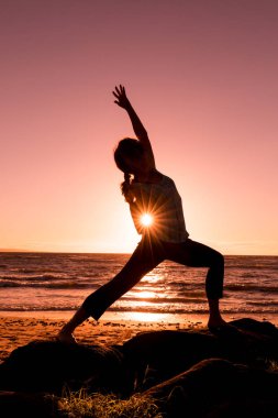 gün batımında sahilde Yoga uygulamak