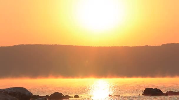 Brouillard matinal au-dessus du lac sous les rayons du soleil. Scène orange — Video