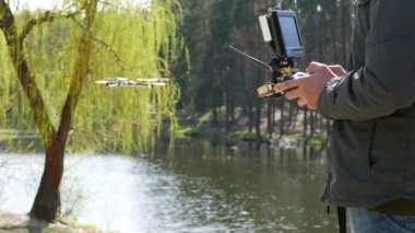 Adam casus uçak operatör verici tutan gölet ve güzel ağaç karşı. 4k 3840 x 2160