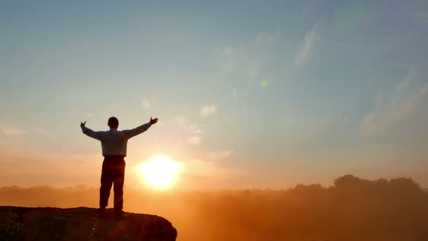 Бизнесмен (молитва) медитирует на вершине горы на красном восходе солнца. 4K 3840x2160 — стоковое видео