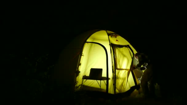 Silhouette touristique pour homme avec tente le soir au travail sur ordinateur portable. 4K 3840x2160 — Video