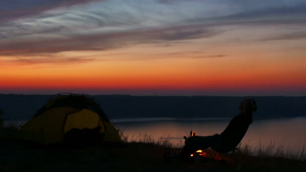 4k Zelt, Lagerfeuer, Sonnenaufgang und Mann Silhouette in der Nähe des Sees. — Stockvideo