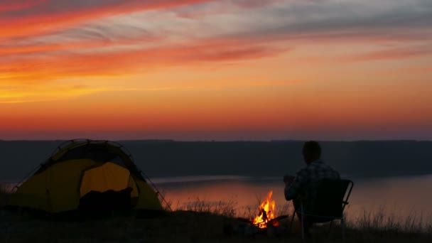 4 k. mężczyzna oczekiwania sunrise z kawy lub herbaty, w pobliżu jeziora. — Wideo stockowe