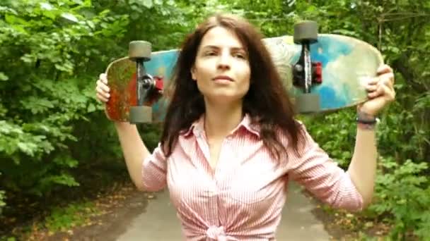 4К. Молодая красивая девушка-подросток фигурка идет со скейтбордом, устойчивый выстрел — стоковое видео