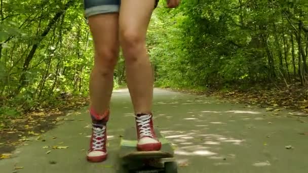 4K. Young beautiful  slendergirl  goes on  skateboard in summer park — Stock Video
