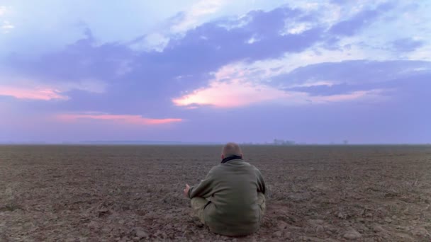 Man mediterar i fältet.4k tidsfördröjning. RAW-utgång, utan fåglar. — Stockvideo