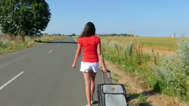4K.   Woman  in red  blouse with  suitcase  go on  road Steady shot — Stock Video