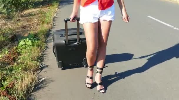 4K. Доросла сексуальна жінка з довгими ногами з валізою на дорозі . — стокове відео