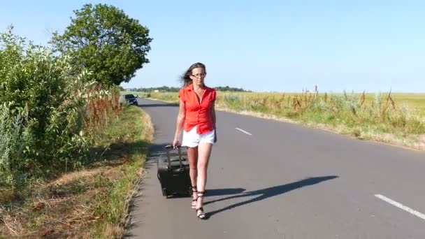 4K. Femme sexy adulte en chemisier rouge avec valise sur la route. Tir stabilisé — Video