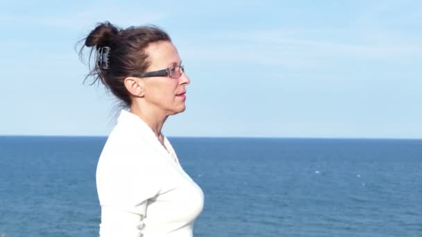 4K.Adult mujer en gafas y blusa blanca contra la superficie del mar — Vídeos de Stock