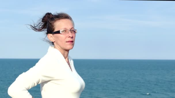 4k. Dospělé ženy v brýle a bílá halenka proti mořské hladiny