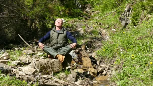 4K. Meditación de día cerca del hermoso arroyo de montaña. Hombre adulto — Vídeos de Stock