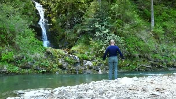 4k. Meditatie van volwassen man in de buurt van kleine waterval. Focus wijzigen — Stockvideo
