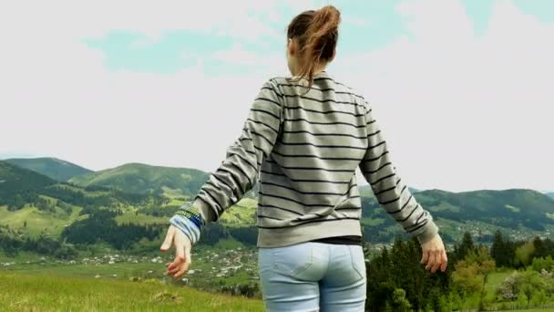 4K. Young girl tourist raises hands up, enjoys life in mountain hills. Steady shot — Stock Video