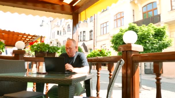 4 k. vuxen man i glasögon i gatan caf verk på laptop. Fokus ändras — Stockvideo