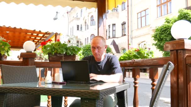 4 k. dospělý muž v brýlích v ulici caf funguje na notebooku — Stock video