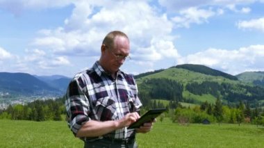 4k. Dağ tepe üzerinde yetişkin adam işime tablet bilgisayar ve gülümseme. Odak Değiştir