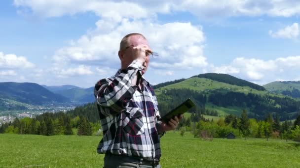 4K. Homem adulto em montanhas monte usar tablet computador. Mudança de foco — Vídeo de Stock